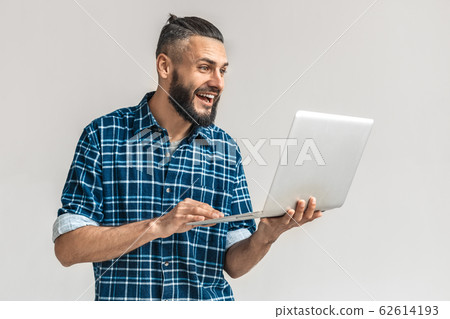 Freestyle. Guy in checkered shirt standing isolated on white playing game on laptop smiling excited Freestyle. Guy in checkered shirt standing isolated on white playing game on laptop smiling excited 62614193