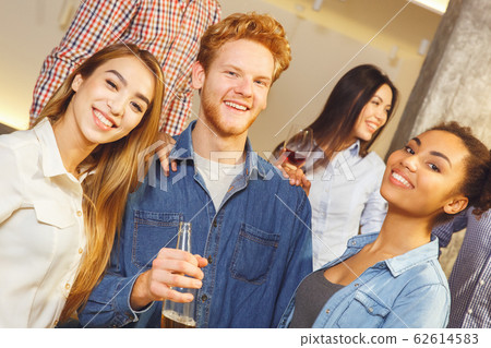 Group of friends having party indoors fun together standing looking camera Group of friends having party indoors fun together standing looking camera 62614583