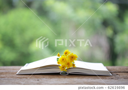 Yellow Chrysanthemum flowers with open notebook on wooden table  62619896