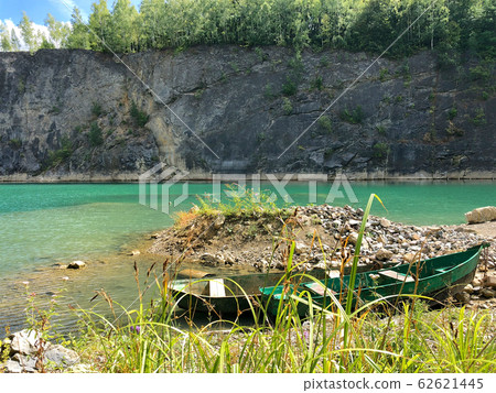 Abandoned boat in flooded quarry with blue crystal water. 62621445