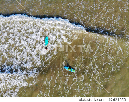 Aerial view of surfers waiting the waves in the dark, brown water in Bali, Indonesia 62621653