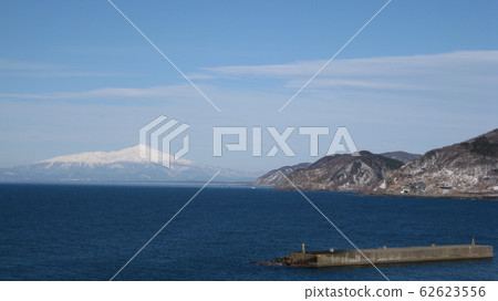 在日本海中漂浮的白雪皚皚的高海山和沿海山脈及防波堤 在日本海中漂浮的白雪皚皚的高海山和沿海山脈及防波堤 62623556