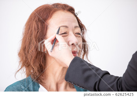 美容人員化妝的中老年女人(眉毛) 美容人員化妝的中老年女人(眉毛) 62625425