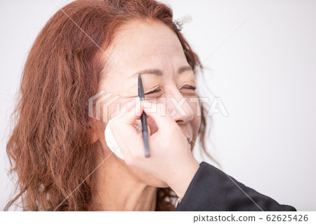 美容人員化妝的中老年女人(眉毛) 美容人員化妝的中老年女人(眉毛) 62625426