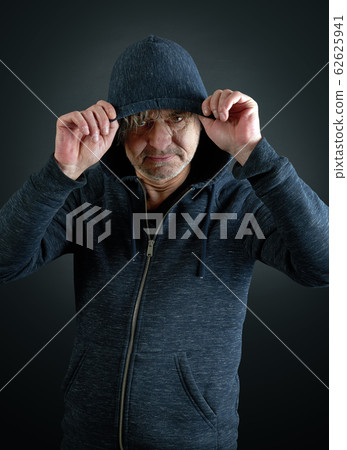 Portrait of a man holding his hooded shirt on Portrait of a man holding his hooded shirt on 62625941