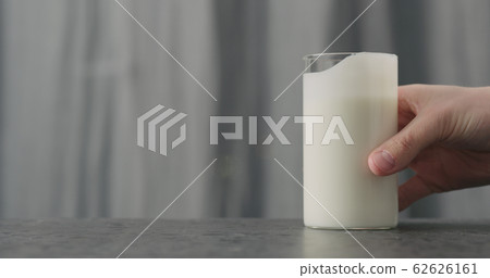 man hand take glass with white yogurt on concrete countertop 62626161