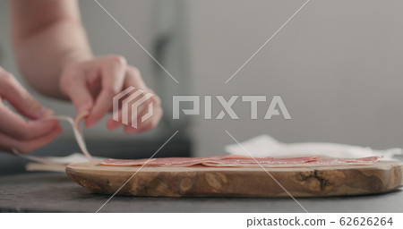 man unpack prosciutto on olive board 62626264