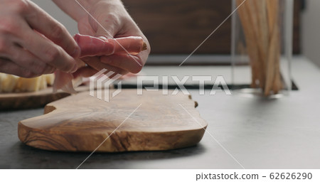 man wrap grissini with prosciutto on olive board man wrap grissini with prosciutto on olive board 62626290