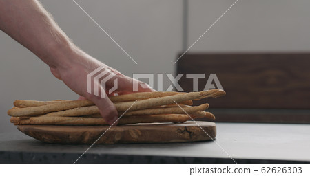 man hand put bunch of homemade grissini on olive board man hand put bunch of homemade grissini on olive board 62626303