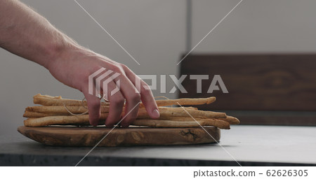man hand take bunch of homemade grissini from olive board man hand take bunch of homemade grissini from olive board 62626305