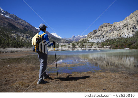 Man standing to look at view of lake with snow Man standing to look at view of lake with snow 62626816