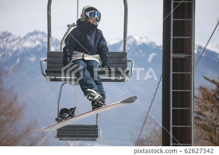 Woman snowboarder riding a lift 62627342