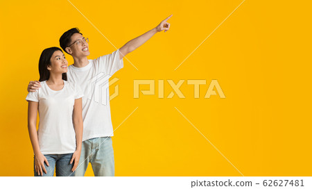 Happy asian man and woman pointing at empty space Happy asian man and woman pointing at empty space 62627481