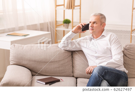 Senior man talking on mobile phone at his home 62627497