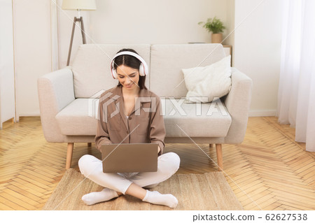 Girl listening to music online in headphones on the floor Girl listening to music online in headphones on the floor 62627538