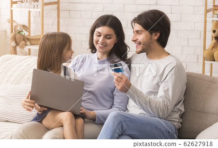 Modern Family With Little Daughter Using Laptop Computer And Credit Card 62627918