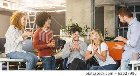 Young creative team cheering new comer girl in office Young creative team cheering new comer girl in office 62627986