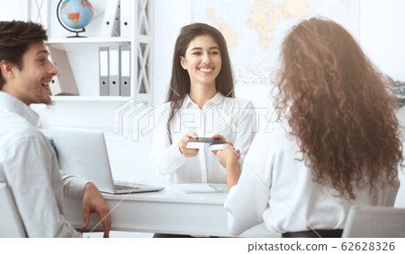 Female travel agent giving tickets to happy couple Female travel agent giving tickets to happy couple 62628326