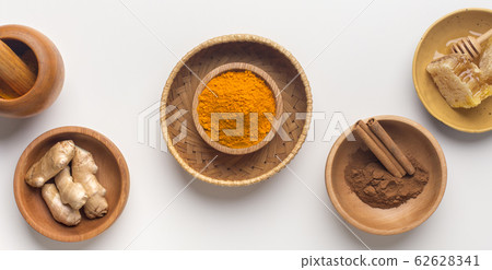 Curcuma powder, cinnamon sticks and honey combs on white 62628341