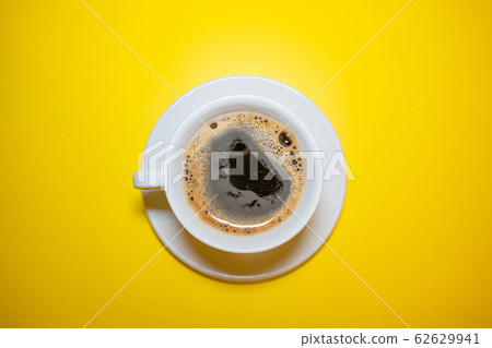 White coffee Cup with foam saucer on a bright yellow background top view White coffee Cup with foam saucer on a bright yellow background top view 62629941