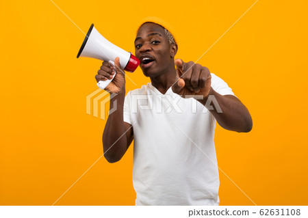 black african man speaks in megaphone on isolated yellow background black african man speaks in megaphone on isolated yellow background 62631108
