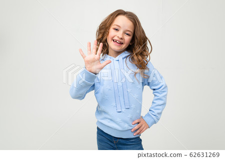 charming teen girl in a blue hoodie shows five fingers on a light gray background 62631269