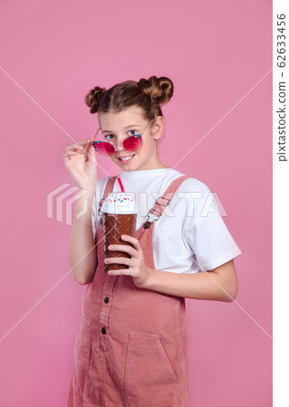 kid girl looking camera lowering sunglasses and drinking cocktail. Summer concept kid girl looking camera lowering sunglasses and drinking cocktail. Summer concept 62633456