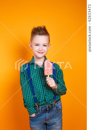 Cute kid boy eating ice cream on yellow background 62633473