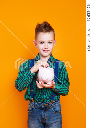 Little boy with piggy bank on yellow background . Financial concept of children's pocket money. Little boy with piggy bank on yellow background . Financial concept of children's pocket money. 62633476