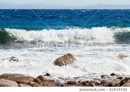 waves and splashes of sea surf and stones on the seashore 62634588