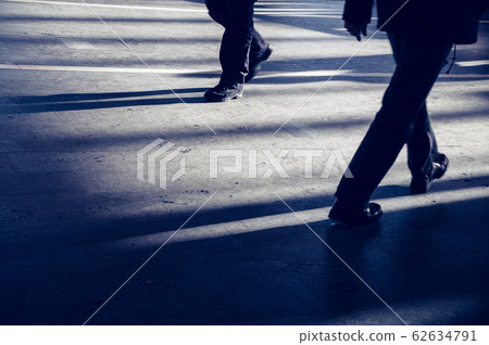 Modern lifestyle ground view of two busy men in different shoes walking with motion blur in urban city subway a weekday morning with dark shadows and sunlight on the street 62634791