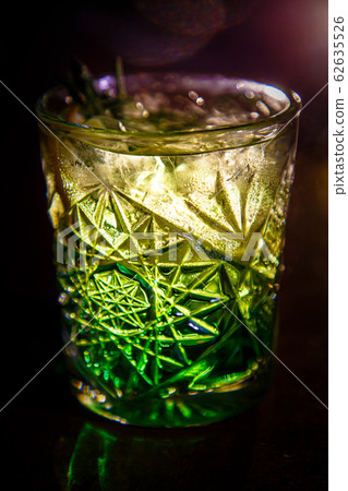A green cocktail in an old fashion glass is on the bar A green cocktail in an old fashion glass is on the bar 62635526