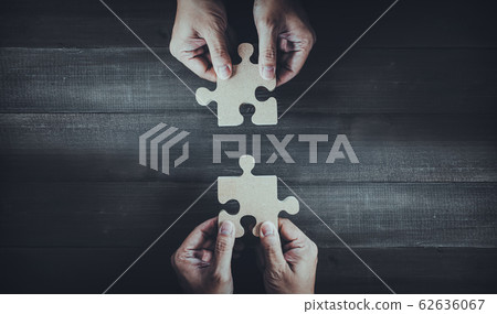 Hands holding wooden jigsaw puzzle pieces and Hands holding wooden jigsaw puzzle pieces and 62636067