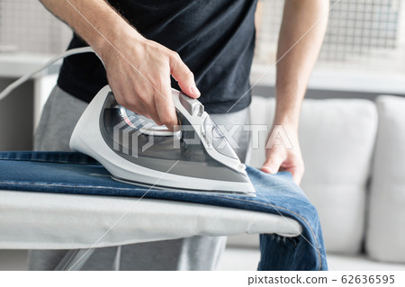 A guy ironing clothes before going outside A guy ironing clothes before going outside 62636595