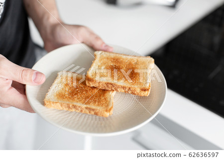 The guy has breakfast with toast with jam. The guy has breakfast with toast with jam. 62636597