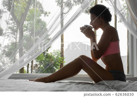 Girl resting and drinking tea in bed with a view Girl resting and drinking tea in bed with a view 62636830