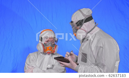 Scientist virologist in respirator makes write in an tablet computer with stylus. Man and woman wearing protective medical mask. Chroma key blue. 62637183