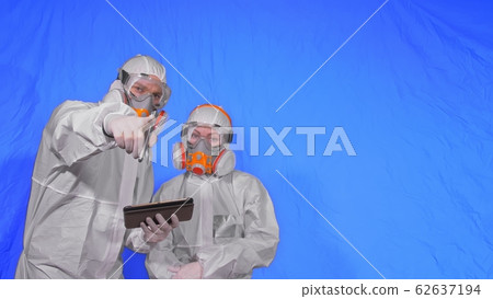 Scientist virologist in respirator makes write in an tablet computer with stylus. Man and woman wearing protective medical mask. Chroma key blue. 62637194