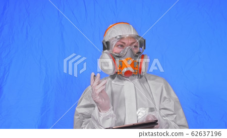 Scientist virologist in respirator makes write in an tablet computer with stylus. Woman wearing protective medical mask. Chroma key blue. 62637196