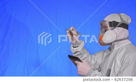 Scientist virologist in respirator makes write in an tablet computer with stylus. Man wearing protective medical mask. Chroma key blue. Scientist virologist in respirator makes write in an tablet computer with stylus. Man wearing protective medical mask. Chroma key blue. 62637206