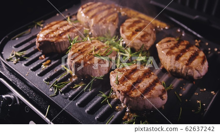 Delicious juicy meat steak cooking on grill. Prime beef fry on electric roaster, rosemary, black pepper, salt. Slow motion. Delicious juicy meat steak cooking on grill. Prime beef fry on electric roaster, rosemary, black pepper, salt. Slow motion. 62637242