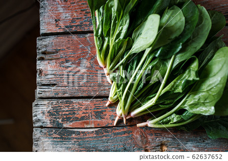 A bunch of young fresh juicy green spinach on a rustic wooden old-time red background. Flat lay A bunch of young fresh juicy green spinach on a rustic wooden old-time red background. Flat lay 62637652
