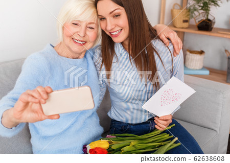 Handsome mom is hugging her daughter and making selfie Handsome mom is hugging her daughter and making selfie 62638608