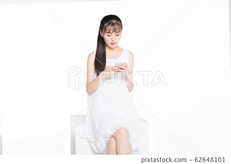 young woman using smartphone against white young woman using smartphone against white 62648101