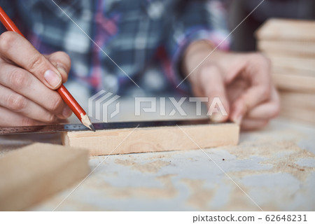 Carpenter hands taking measurement with a pencil Carpenter hands taking measurement with a pencil 62648231
