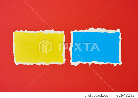 Two ripped paper torn edge sheets on a red Two ripped paper torn edge sheets on a red 62648252