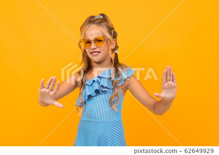 Cheerful girl in dress smiles says stop isolated on yellow and orange background 62649929