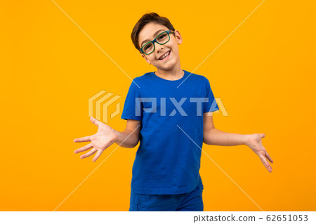 handsome teenager boy in a blue t-shirt with glasses holds out his hands in different directions on 62651053