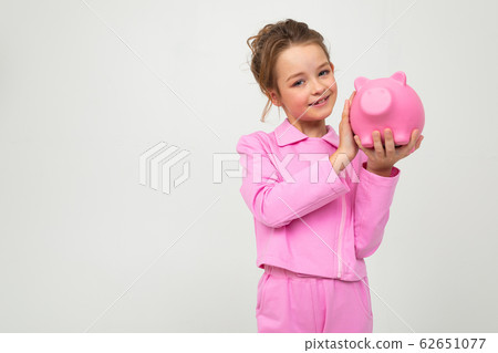 finance. young cute girl in a pink suit holds a piggy bank on a white background with copy space 62651077