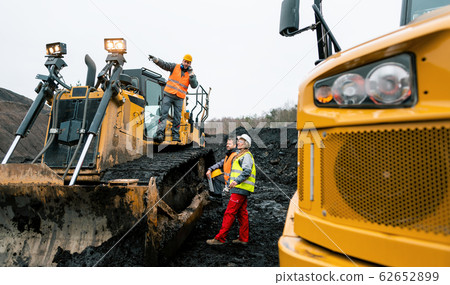 Heavy machinery and workers in pit of quarry 62652899